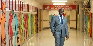 jabari whitehead, ed.d., wearing a suit and standing inside an elementary school hallway