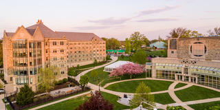 Two large stone buildings separated by a lush green field on the campus of Saint Joseph's University Hawk Hill campus