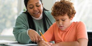 Teacher working with elementary age student on an assignment
