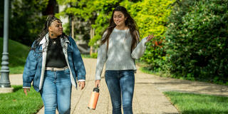 Two students having a conversation walking outside on a sunny day