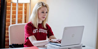 Female Saint Joseph's student working on her laptop
