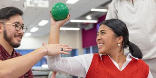 Saint Joseph's University student assistant a person with a physical therapy exercise with a ball