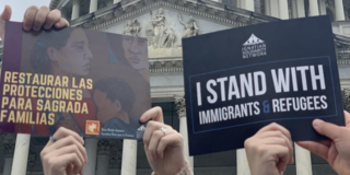 Two signs being held up in support of immigrant refugees