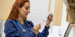 a nursing student in scrubs getting a syringe ready