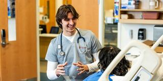 Nursing student speaking with a patient in a hospital room