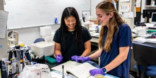 two McNulty students in microbiology lab_looking at a logbook_2400 X 1300