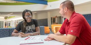 Male advisor working with female student on paperwork