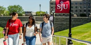 Three students walking in front of post crossing at Saint Joseph's University