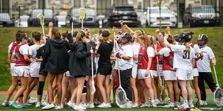 Saint Joseph's women's lacrosse team in field in team huddle