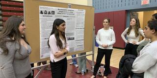 A student is presenting a poster to an audience.