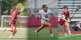 Three female lacrosse players on field