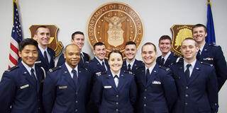 Air Force Officers smiling in front of Air Force shield