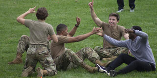 Air Force ROTC members sitting on the ground and celebrating