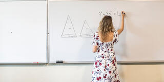student working a math problem at a whiteboard