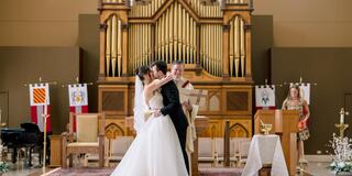 Bride and groom kissing in front of altar