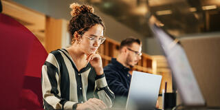 student looking down at laptop on table