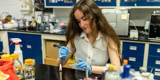 McNulty Scholar_Clare McGlaughlin_using a pipette and holding a Petri dish_2500x1550