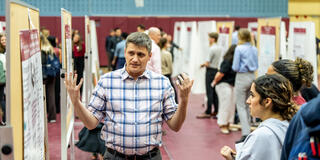 professor talking to female students while pointing at poster
