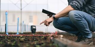 a man checking the soil inside a greenhouse