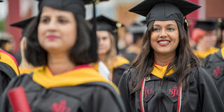 An adult student smiles in her cap and gown at graduation