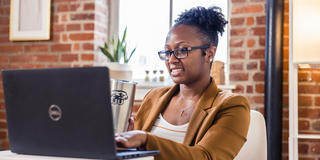 a female student wearing glasses typing on a laptop