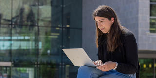 female saint joseph's university student on her laptop outside