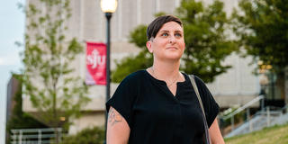 female graduate student with short hair walking outside on saint joseph's university's campus