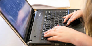 student typing on a laptop