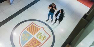 Two students walk near the seal on the floor of mandeville hall