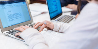 students typing on a laptop