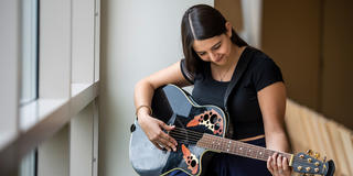 female saint joseph's university student playing the guitar