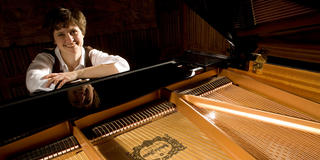 A woman sitting behind a piano