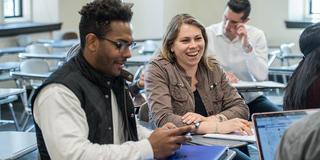 two saint joseph's university talking to each other in a classroom