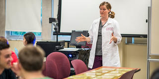 saint joseph's university professor in a lab coat teaching students in classroom
