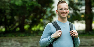 student with glasses wearing a blue shirt and a backpack