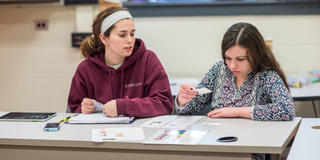 two female students working together inside a classroom