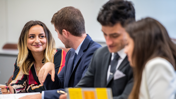 A group of business students collaborate over textbooks and notes