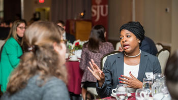 A group of law alumni chat at a table