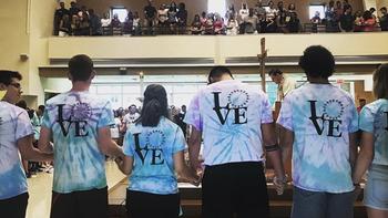 A group of students standing in a church wearing colorful shirts