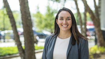 A young woman who is an insurance major smiles in a blazer