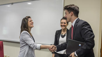 A woman and a man shake hands wearing suits