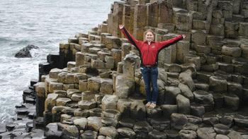 A Saint Joseph's University student stands with her arms open at Giant's Causeway in Northern Ireland