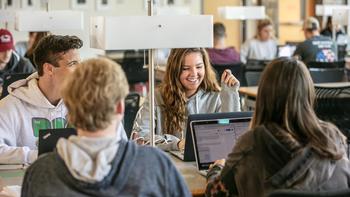 Students talk across tables in the library