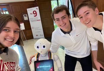 Three students pose with Pepper the robot 