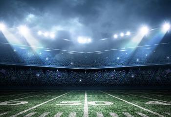 A football field with spotlights shining down at night
