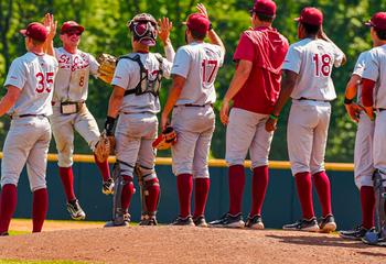 Saint Joseph's baseball team high fiving one another on the field
