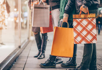 People window shopping while holding holiday bags in their hands. 