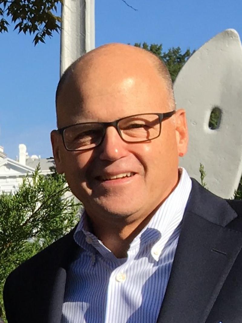 a man wearing a light blue collared shirt and suit coat, standing outside
