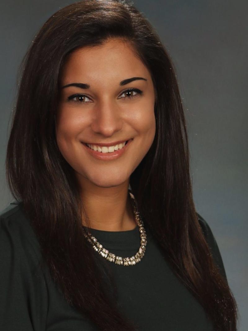 Rachel wears a black dress and a silver necklace in her headshot