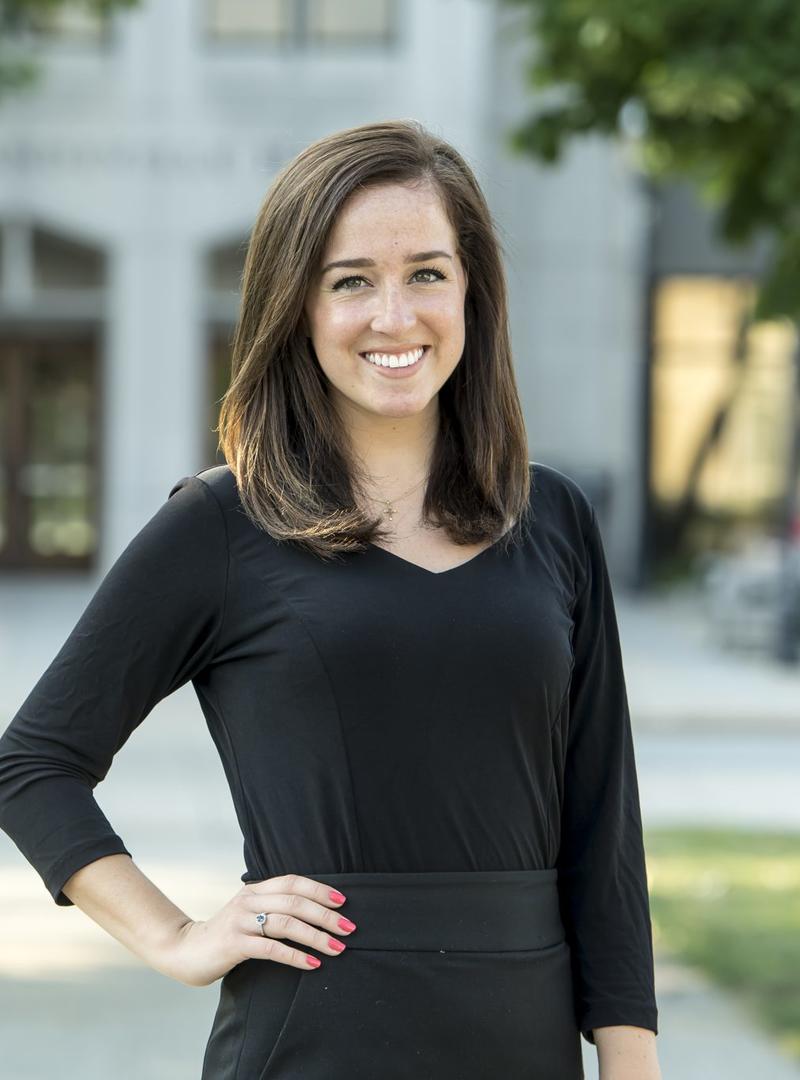 Mary has her hand in her hip and smiles at the camera